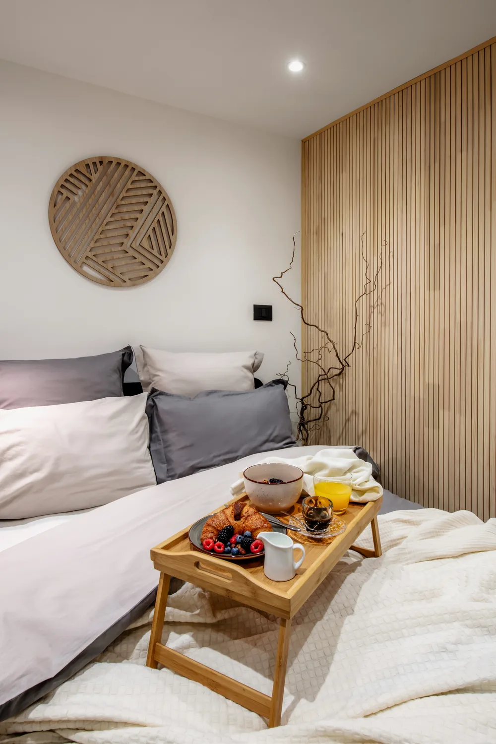 Frühstückstablett auf dem Bett, mit Holzwand und rundem Wandschmuck