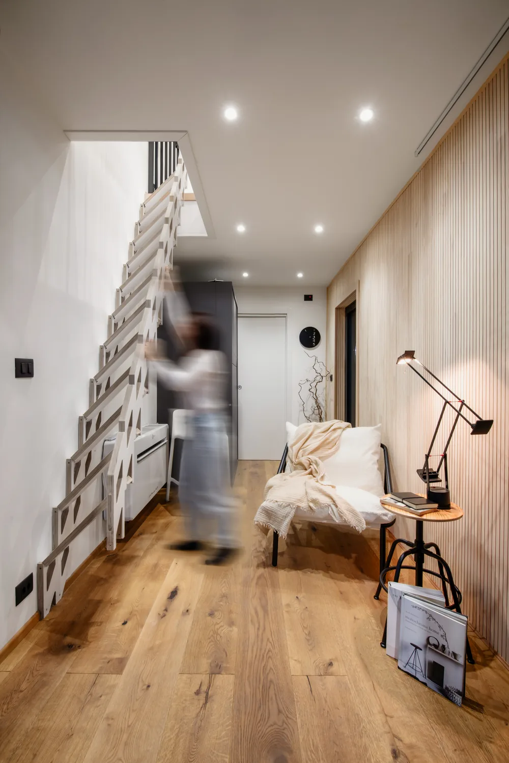Die raumsparende Treppe beim Einklappen an die Wand, mit einer Person in Bewegung
