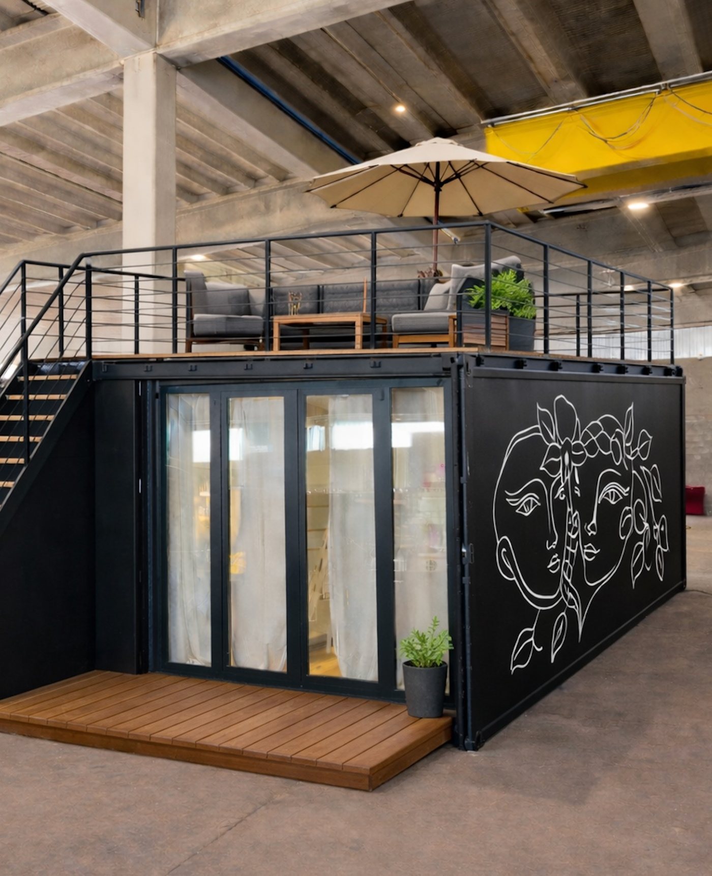 Einzelne 20-Fuss-Einheit mit Dachterrasse, Sonnenschirm und Linienzeichnung an der Wand, in der Werkstatt